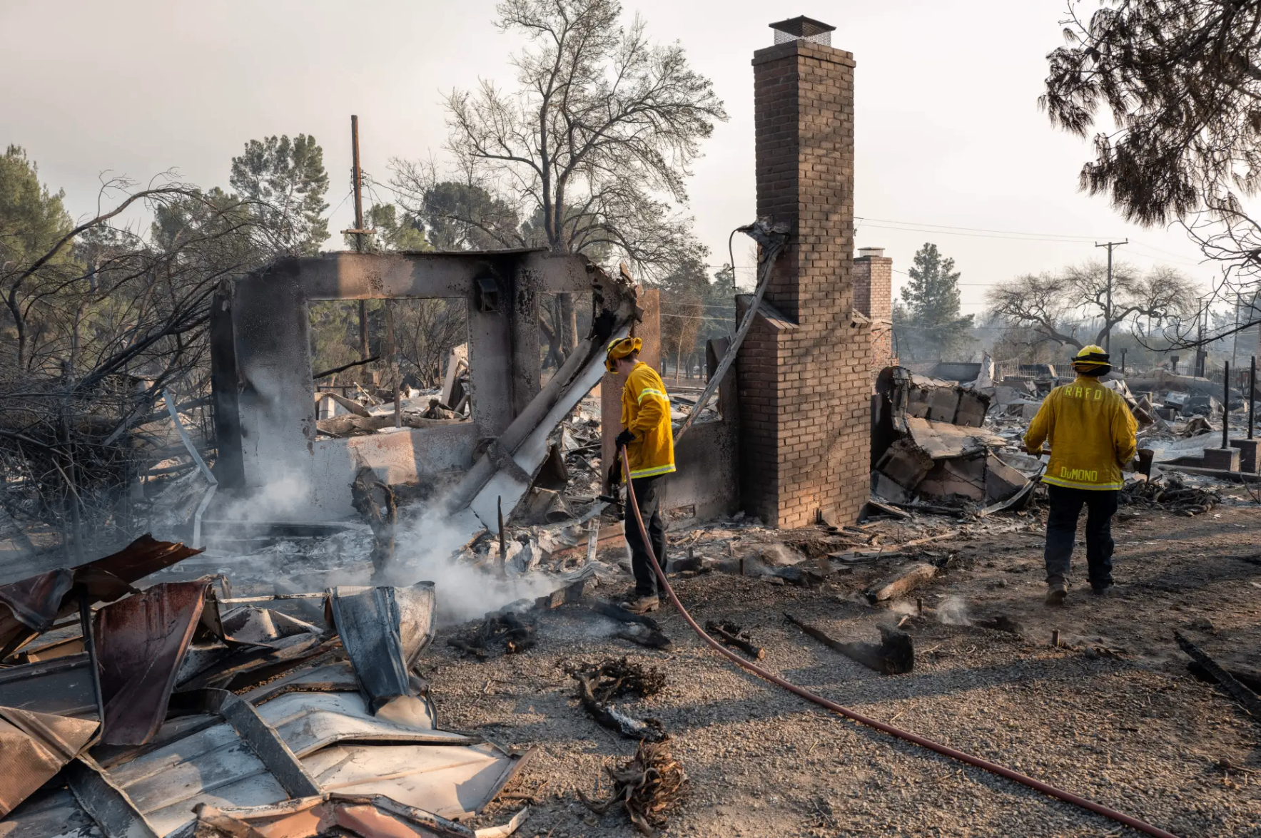 Firefighters extinguishing smoldering debris at a home destroyed by the Eaton Fire in Los Angeles County